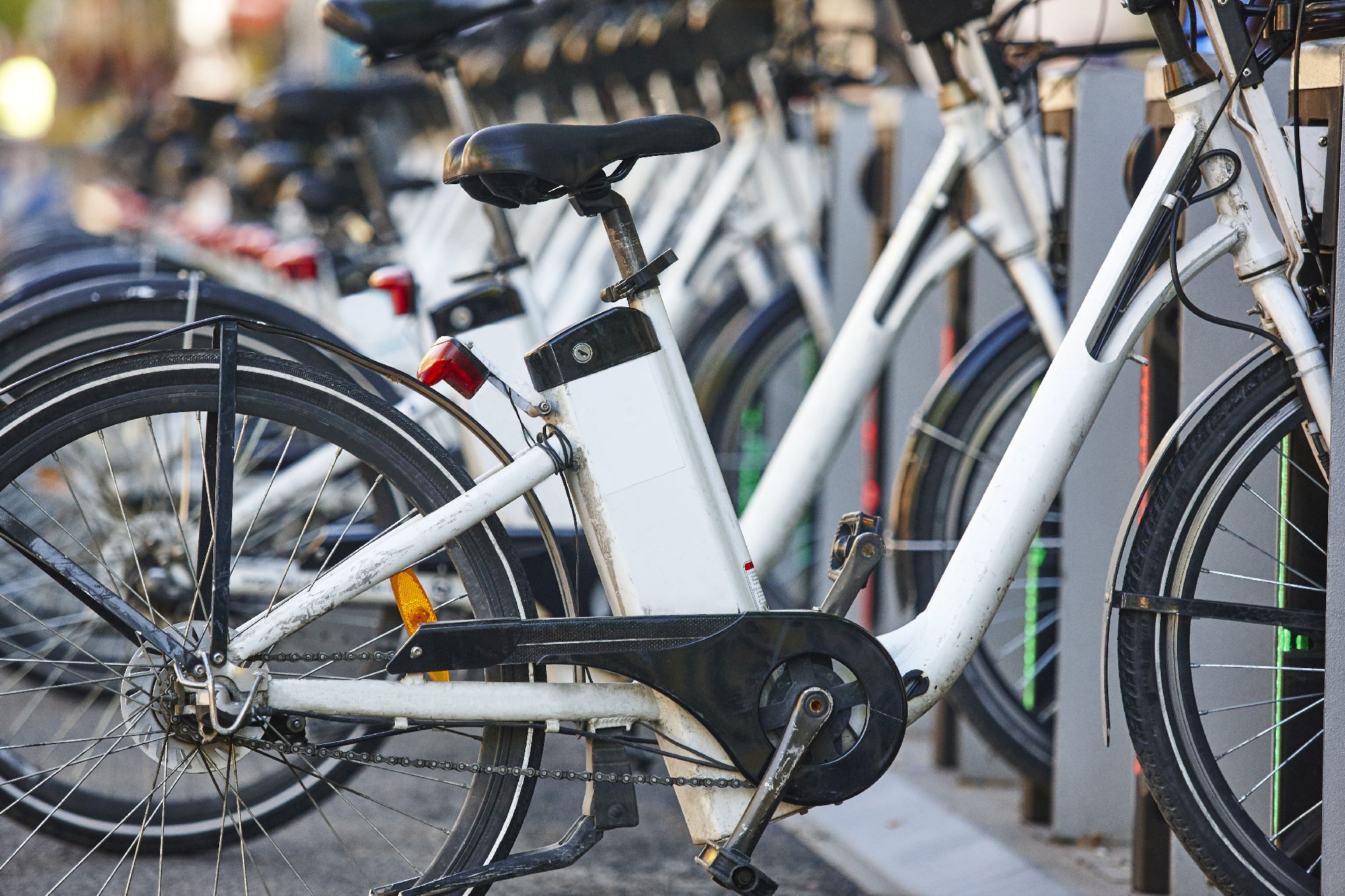 White electric bikes in a line being charged on the street