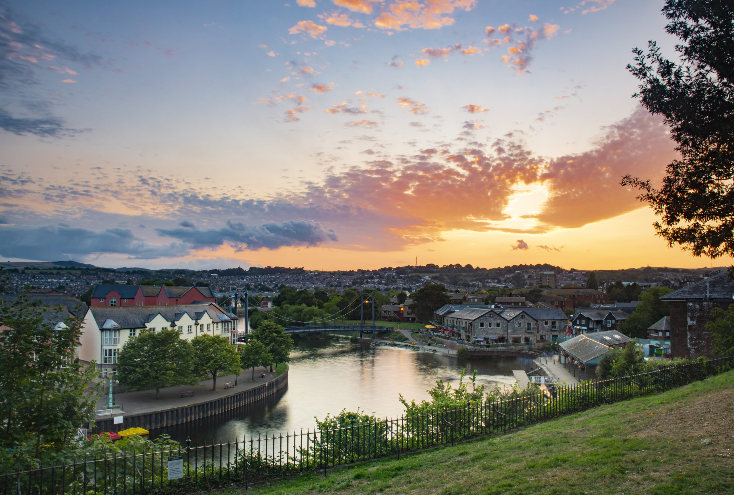 A beautiful sunset over Exeter's Quay with green space in the foreground